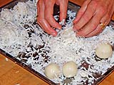 Rolling cooled balls in steamed salted coconut shreds